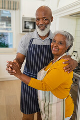 Obraz premium Portrait of senior african american couple in kitchen looking at camera and smiling