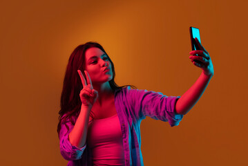 Caucasian young woman's portrait on dark studio background in neon light. Female model in casual...