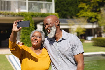 Senior african american couple spending time in sunny garden together taking selfies and smiling