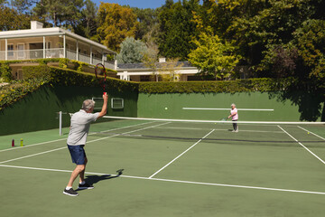 Obraz premium Senior caucasian couple playing tennis together on court