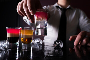 Barman preparing cocktail shots at the bar counter. Barman mixing drinks at the night club