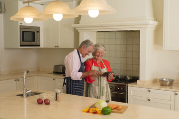 Senior caucasian couple using tablet together in kitchen