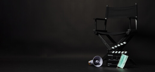 Black director chair , face mask, megaphone and Clapper board or movie slate on black background.