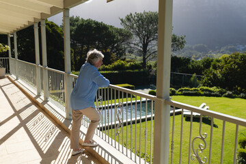 Senior caucasian woman standing on balcony and looking away