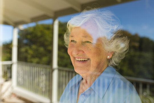 Senior caucasian woman looking through window and smiling