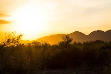 sunset in the desert, the sun sets behind the rocky mountains