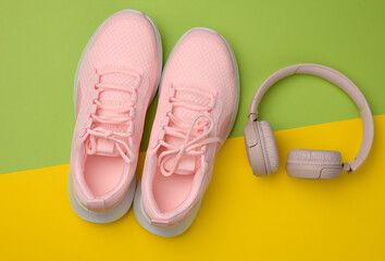 pair of pink sneakers, wireless headphones on a yellow background