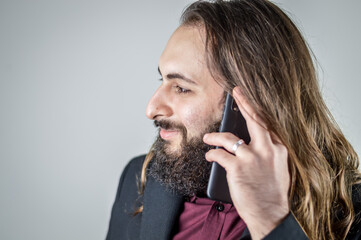 profile portrait of a young middle eastern businessman with beard and long hair while having a conversation on the mobile phone © sebastianosecondi
