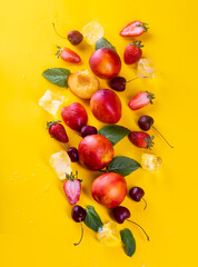 Fruit on a yellow background top view (cherry, peach, strawberry)