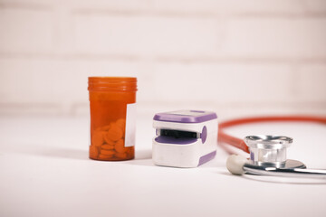 pill container, stethoscope and pulse oximeter on table 