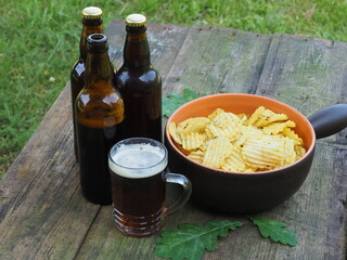 Beer and potato chips. Bottles and a cup of beer on the table. Alcohol and snacks