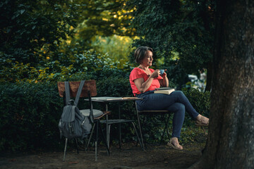 Senior woman reading book in outdoor coffee shop.