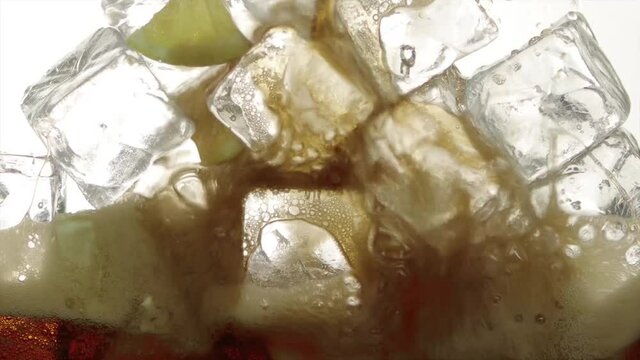 Detailaufnahme von einschenken eines frischem gek&uuml;hltes sprudelndes Cola Getr&auml;nk mit Eisw&uuml;rfel und Zitronenschnitz.