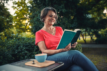 Fototapeta premium Senior woman reading book in outdoor coffee shop.