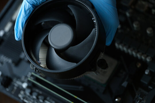 Gloved craftsman installing cooler into video card closeup