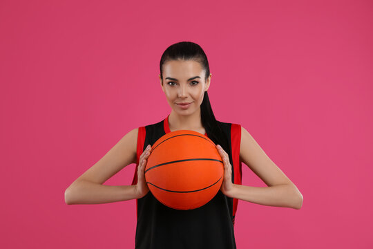 Basketball player with ball on pink background