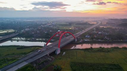 Obraz na płótnie Canvas Aerial view of the Kalikuto Bridge, an Iconic Red Bridge at Trans Java Toll Road, Batang when sunrise. Central Java, Indonesia, July 1, 2021
