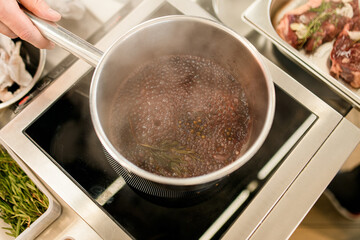 top view of a stainless saucepan with boiling sauce inside it.