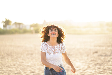 Horizontal portrait of woman running in the beach at sunset. Happiness summer lifestyle concept.