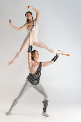 Young couple of ballet dancers in ancient Rome costumes dancing on white studio full of light....