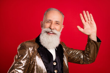 Photo of happy positive young man hold hand wave hello smile good mood theatre isolated on red color background © deagreez