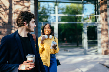 Young handsome caucasian curly man waiting for his girlfriend in the city street, outdoor. Love, relationship, dating: concept.