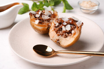 Delicious baked apple halves with nuts and caramel served on white table