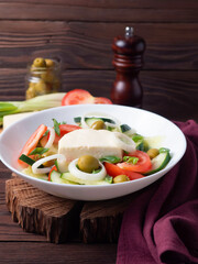Greek salad with juicy tomatoes, feta cheese, green olives, cucumber. Homemade food. A symbolic image. The concept of delicious and healthy vegetarian food.