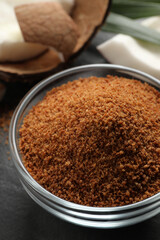 Natural coconut sugar in glass bowl on black table