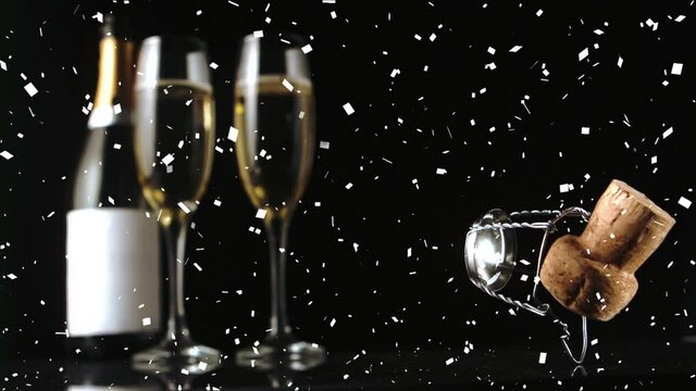 Animation of confetti and champagne cork falling, with bottle and two glasses of champagne, on black