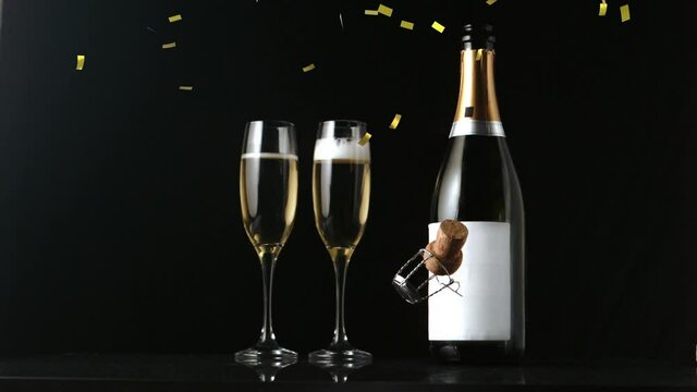Animation of gold confetti and champagne cork falling, with champagne bottle and glasses, on black