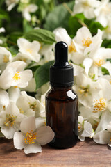 Jasmine essential oil and fresh flowers on wooden table