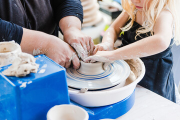 Faceless woman teaching pottery to kid