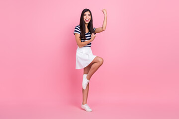 Photo of charming lucky young lady dressed striped clothes smiling rising fists isolated pink color background