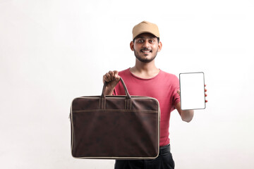 Portrait of a excited happy young delivery man in cap standing over white background. Looking camera showing display of mobile phone.