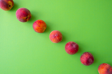 ripe peaches laid out in a line, dividing the green background