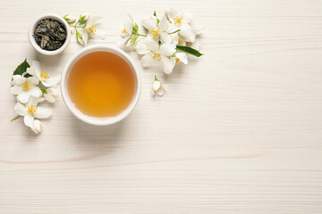Fototapeta na wymiar Aromatic jasmine tea, dry leaves and fresh flowers on white wooden table, flat lay. Space for text