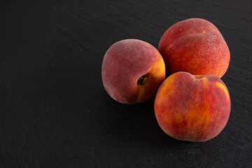 Fototapeta na wymiar three ripe peaches lie on a black background