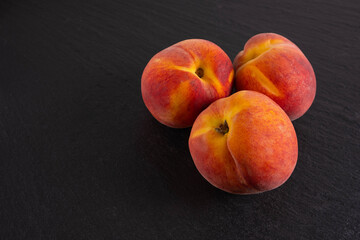 ripe three peaches lie on a black background