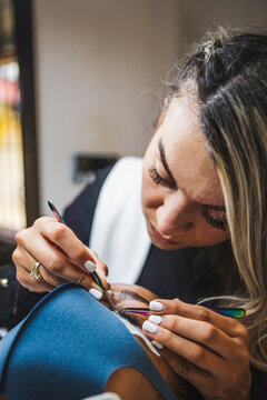 Beautician applying eyelashes on face of black woman