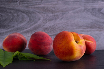 juicy peaches and green foliage lie on a black background