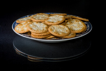 crackers on a plate with black background and copy space