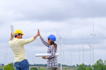 Engineers stand holding blueprints and congratulate wind turbine projects to generate electricity and check wind direction.