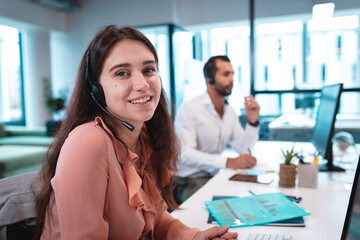 Portrait of caucasian businesswoman wearing headset and sitting at table