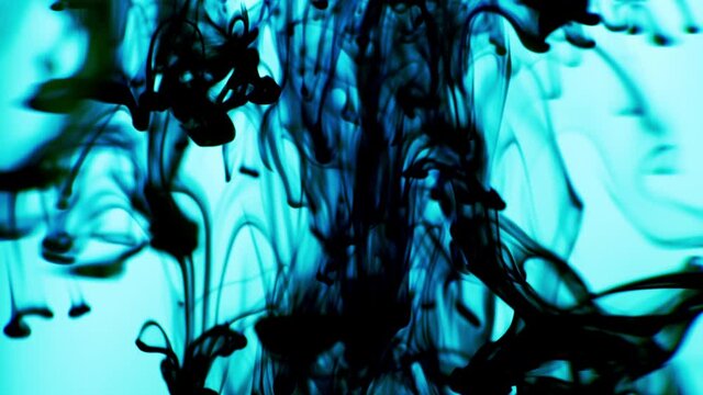 Black Ink Released Above swirling in Water on Light Blue Background