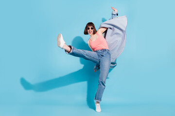 Photo of adorable cool young lady dressed jeans shirt dark glasses smiling dancing walking isolated...