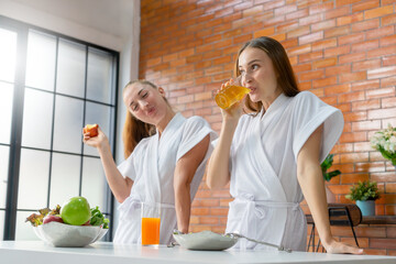 Selective Focus on cheerful woman in white bathrobe drinking fresh fruit juice for a healthy diet after exercise workout at the home in the morning. Concept of clean eating lifestyle, vegetarian food