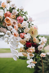 Wedding decorations, details, accessories on a wooden round arch - multicolored flowers, roses...