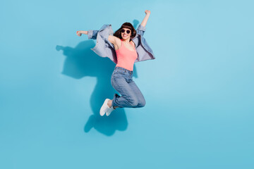Obraz premium Full length body size view of pretty cheerful carefree girl having fun jumping isolated over bright blue color background