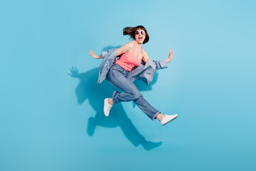 Obraz premium Full size profile photo of hooray young lady jump wear top jeans eyewear isolated on blue color background
